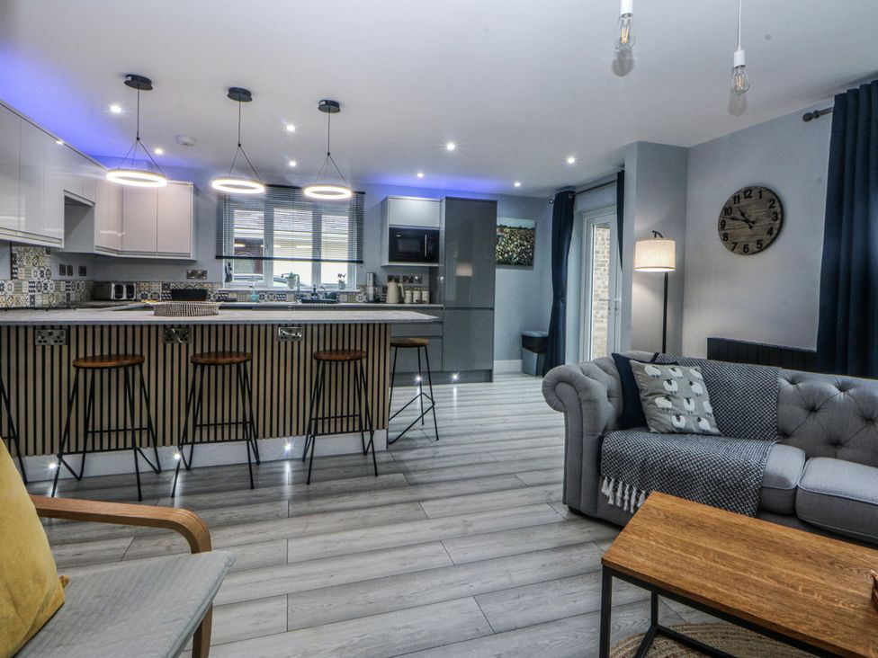 A kitchen with bar stools and oven at Ty Glan Morfa in Morfa Bychan