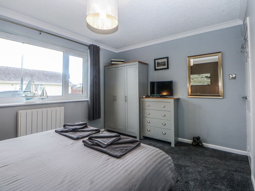 A bedroom with a bed, wardrobe, and dresser at Ty Glan Morfa in Morfa Bychan