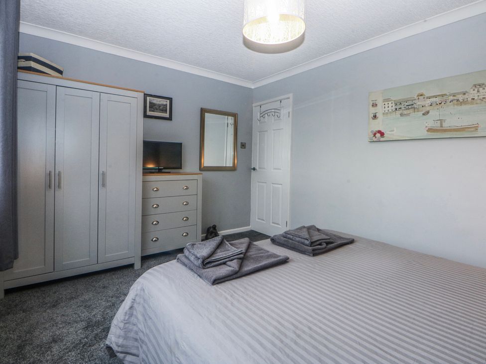 A bedroom with furniture including a bed, wardrobe, and television at Ty Glan Morfa in Morfa Bychan