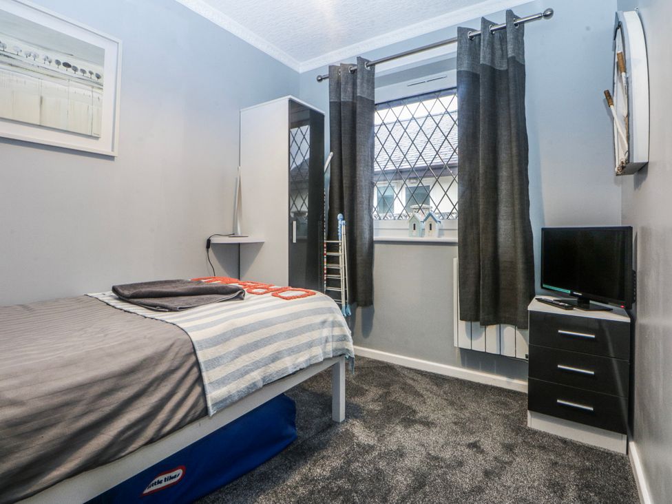 A bedroom with a bed and television at Ty Glan Morfa in Morfa Bychan