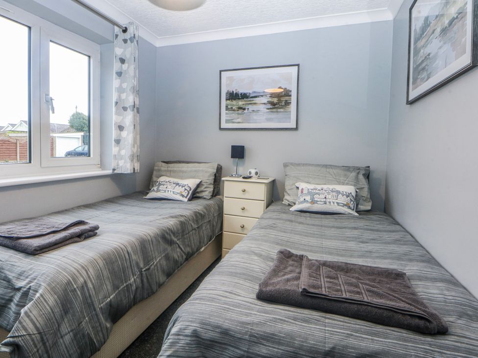 A bedroom with two beds and a bedside table at Ty Glan Morfa in Morfa Bychan