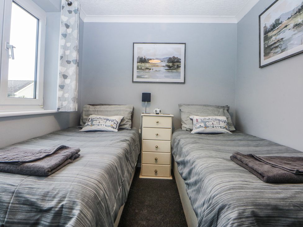 A bedroom with two single beds and a nightstand at Ty Glan Morfa in Morfa Bychan