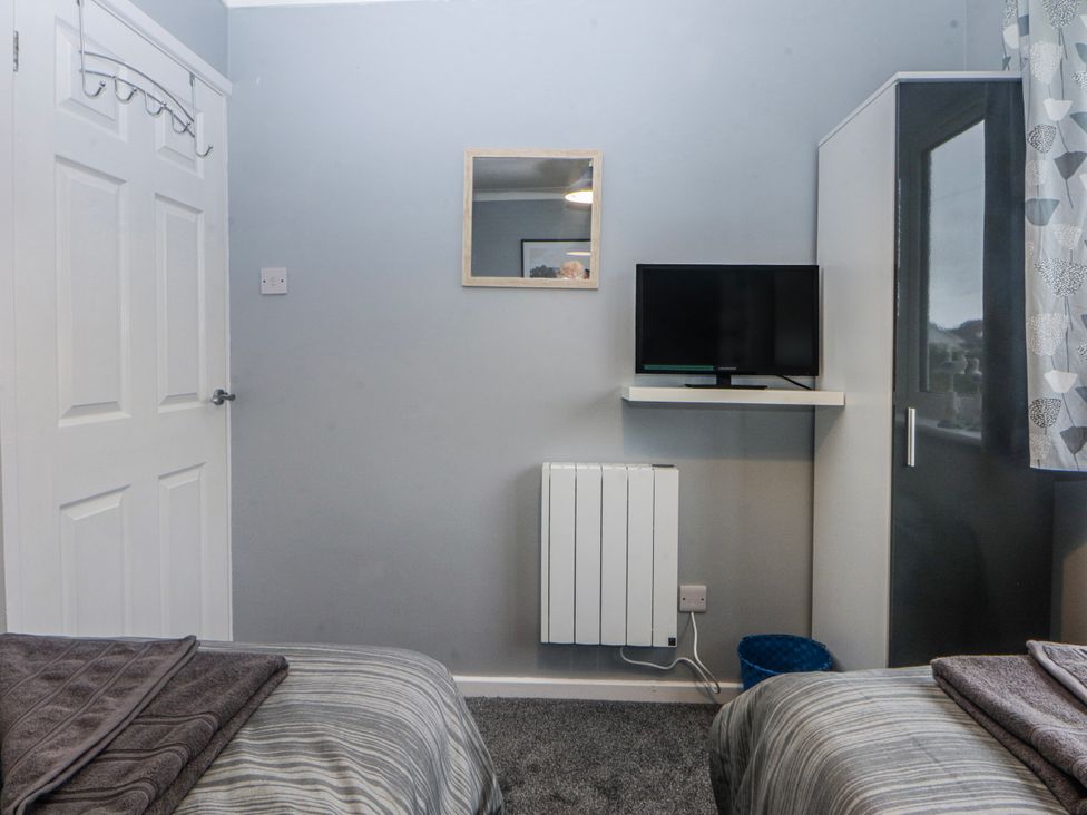 A bedroom with a television on a wall shelf at Ty Glan Morfa in Morfa Bychan