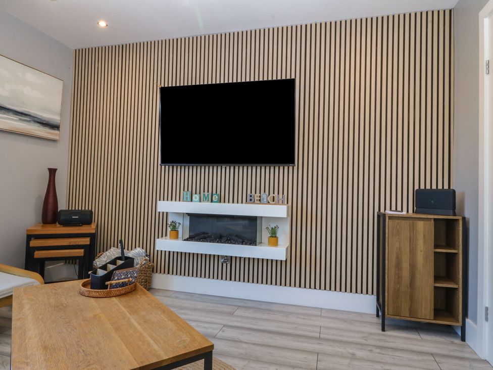 A living room with a television and fireplace at Ty Glan Morfa in Morfa Bychan
