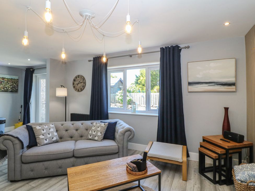 A living room with a sofa, table, and window at Ty Glan Morfa in Morfa Bychan