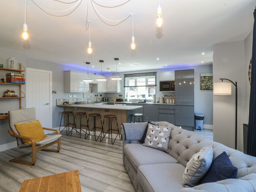 A living room with a kitchen island and bar stools at Ty Glan Morfa in Morfa Bychan