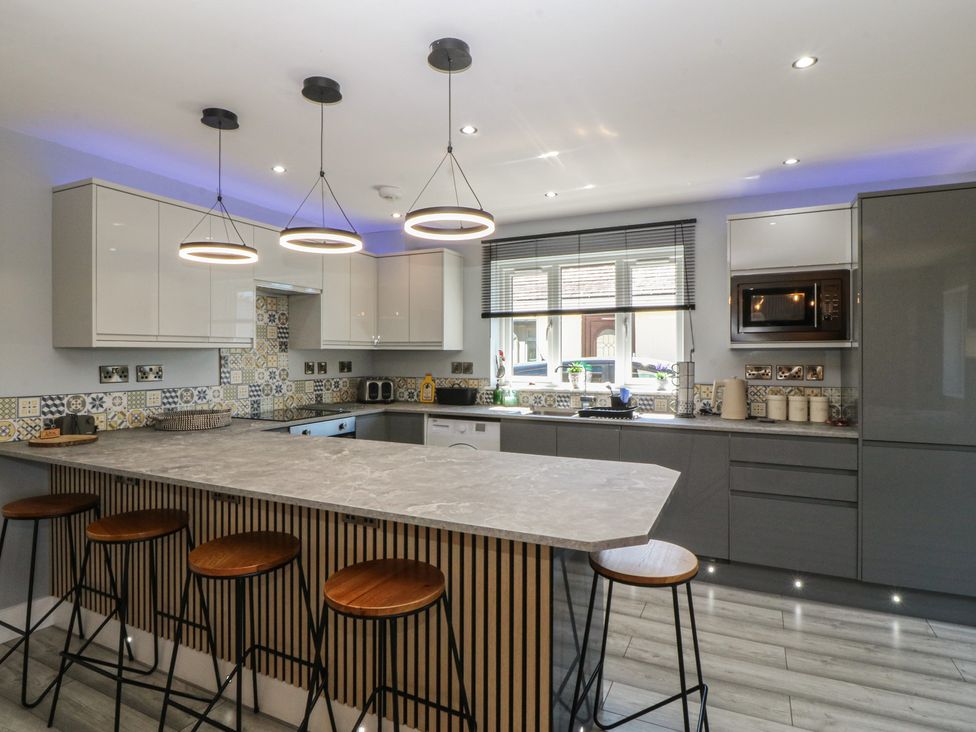 A kitchen with an island and bar stools at Ty Glan Morfa in Morfa Bychan