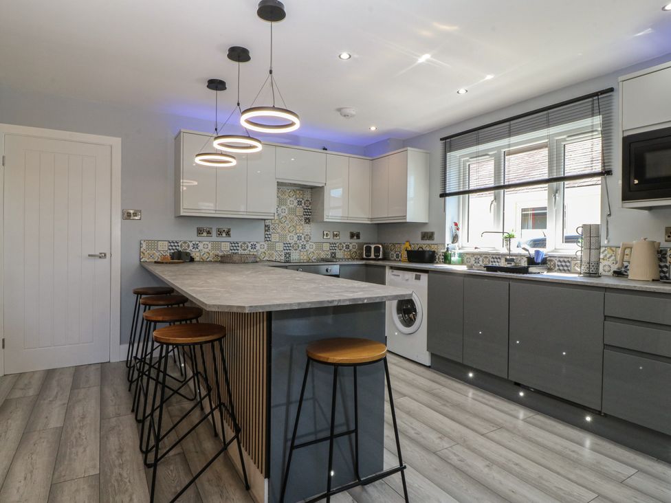 A kitchen with bar stools and countertop at Ty Glan Morfa in Morfa Bychan