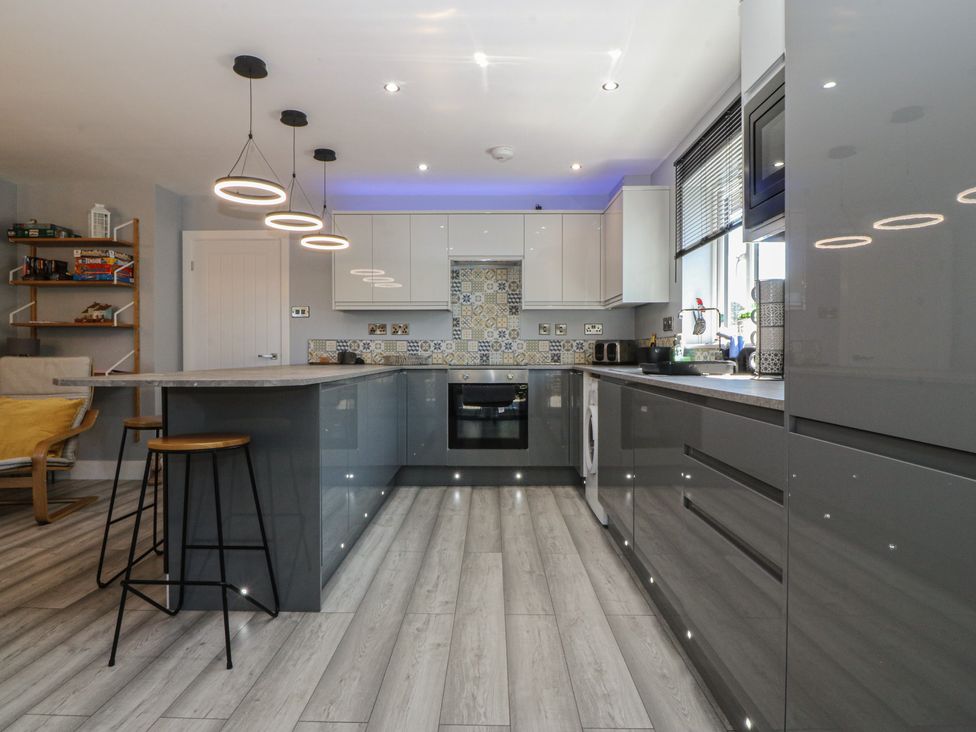 A kitchen with a countertop and bar stools at Ty Glan Morfa in Morfa Bychan
