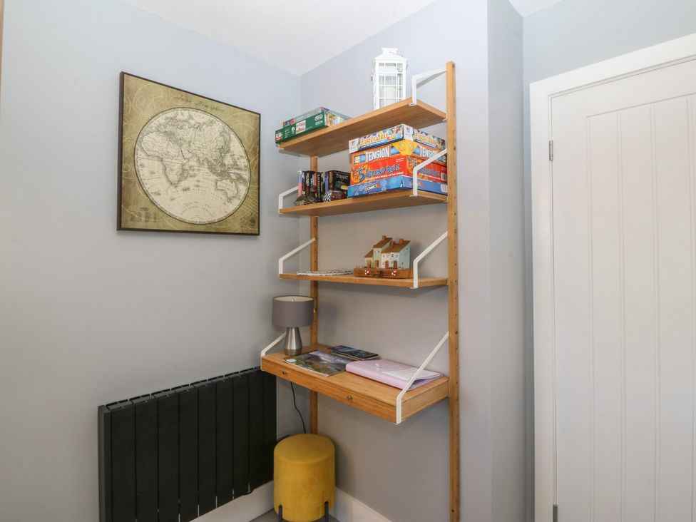 A shelf with games and decorative items in the hallway at Ty Glan Morfa Morfa Bychan