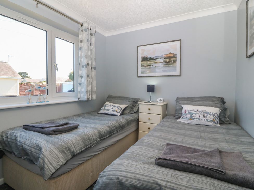 A bedroom with two single beds and a bedside table at Ty Glan Morfa in Morfa Bychan