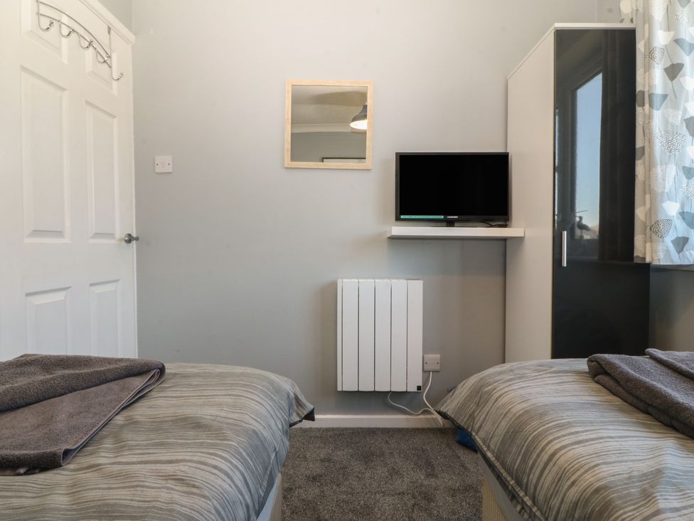 A bedroom with a television and twin beds at Ty Glan Morfa in Morfa Bychan
