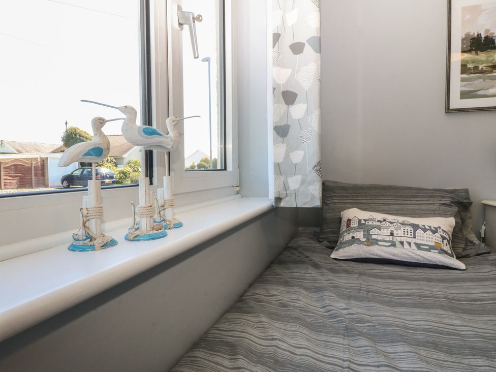 A bedroom with a window and decorative birds on the sill at Ty Glan Morfa in Morfa Bychan