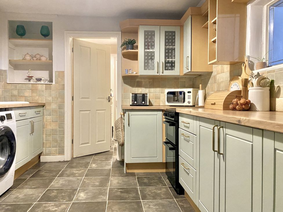 A kitchen with cabinets and appliances at Waterfall Cottage in Dyserth