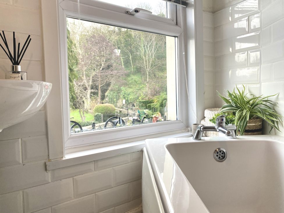 A bathroom with a bathtub and sink overlooking a garden at Waterfall Cottage Dyserth