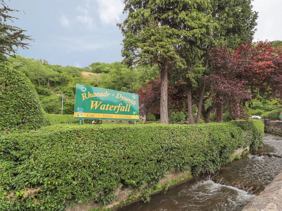 An outdoor area with a sign and trees at Waterfall Cottage in Dyserth