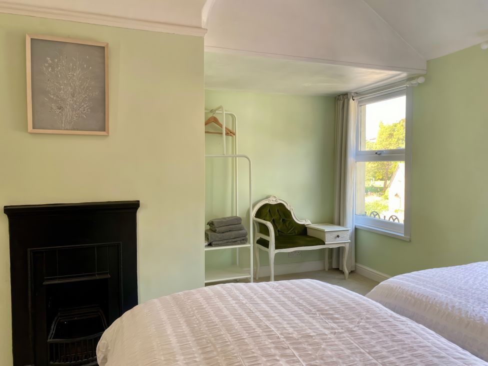 A bedroom with two beds and a chair at Waterfall Cottage in Dyserth