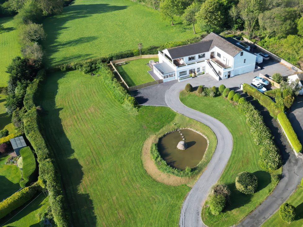 A house with a pond and landscaped garden at Top Of The Lane Luxury Holiday Apartment in Benllech