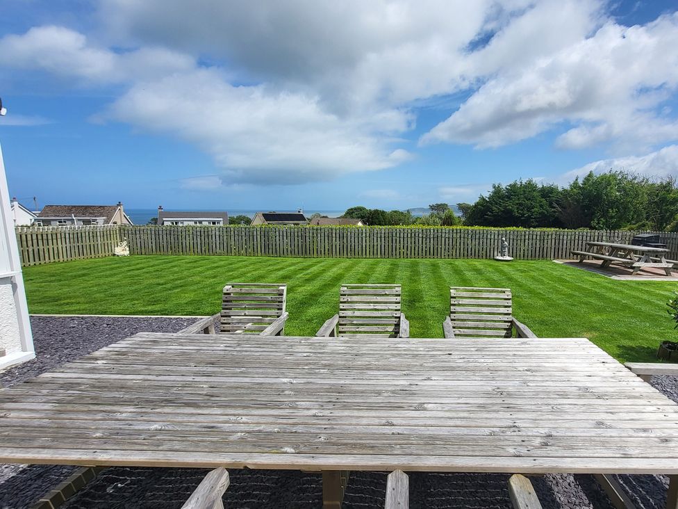 A garden with a wooden table and chairs at Top Of The Lane Luxury Holiday Apartment Benllech
