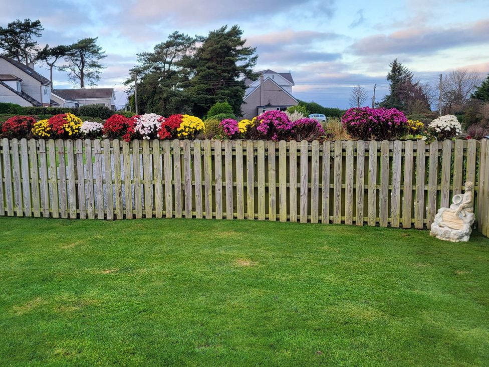 A garden with a wooden fence topped with flowers at Top Of The Lane Luxury Holiday Apartment in Benllech