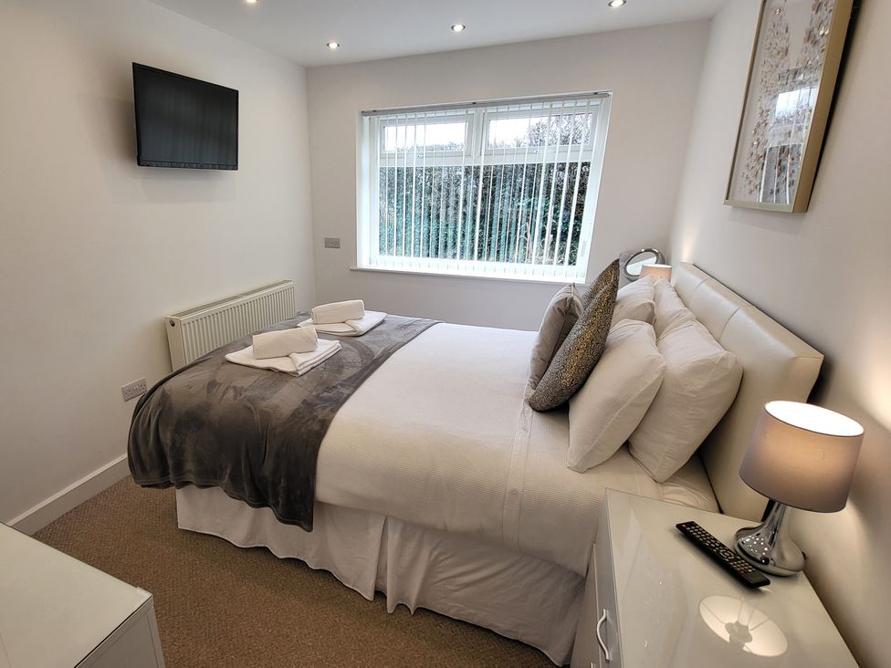 A bedroom with a bed and television at Top Of The Lane Luxury Holiday Apartment in Benllech