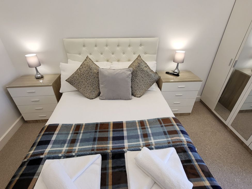 A bedroom with a bed and bedside tables at Top Of The Lane Luxury Holiday Apartment in Benllech