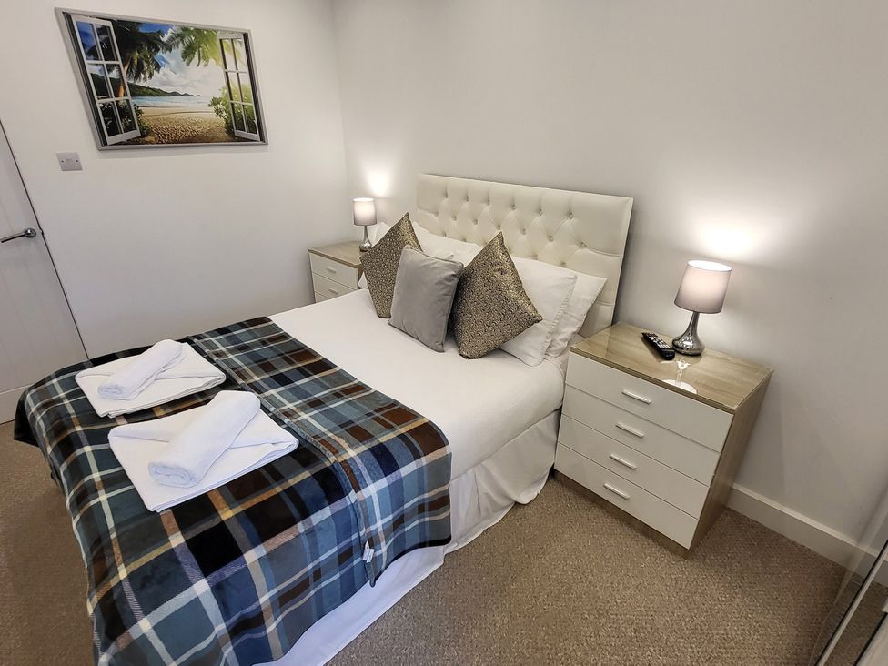 A bedroom with a bed, pillows, and nightstand at Top Of The Lane Luxury Holiday Apartment Benllech
