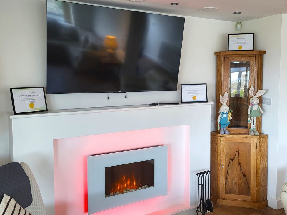 A living room with a television and fireplace at Top Of The Lane Luxury Holiday Apartment in Benllech