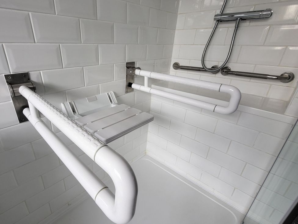 A shower area with grab bars and a shower seat at Top Of The Lane Luxury Holiday Apartment in Benllech