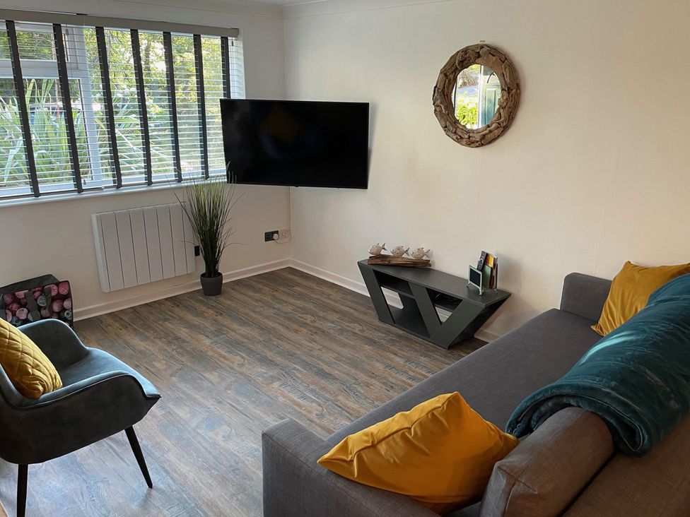 A living room with a TV and sofa at 51 Fernhill Heights in Charmouth