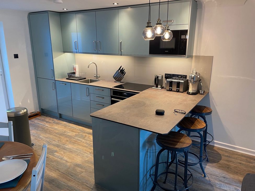 A kitchen with cabinets, sink, stove, and bar stools at 51 Fernhill Heights Charmouth