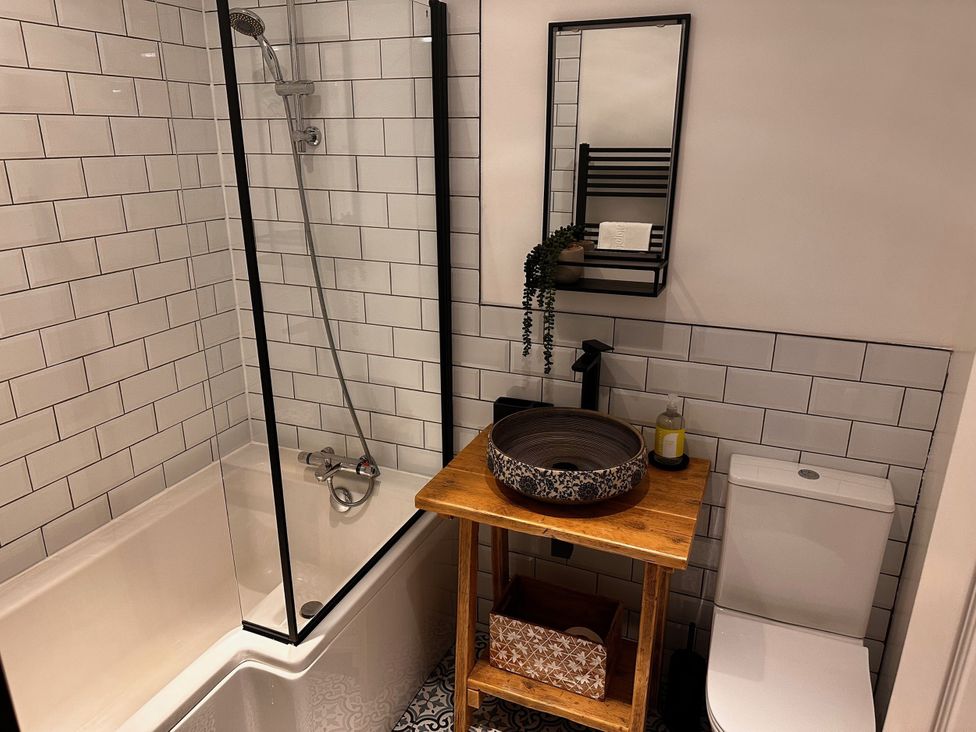 A bathroom featuring a bathtub, shower, toilet, and sink at 51 Fernhill Heights in Charmouth
