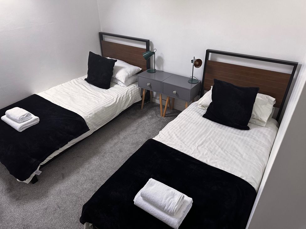 A bedroom with two beds and a nightstand at 51 Fernhill Heights Charmouth
