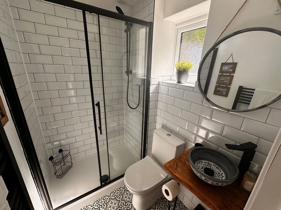 A bathroom with shower, toilet, sink, and mirror at 51 Fernhill Heights in Charmouth