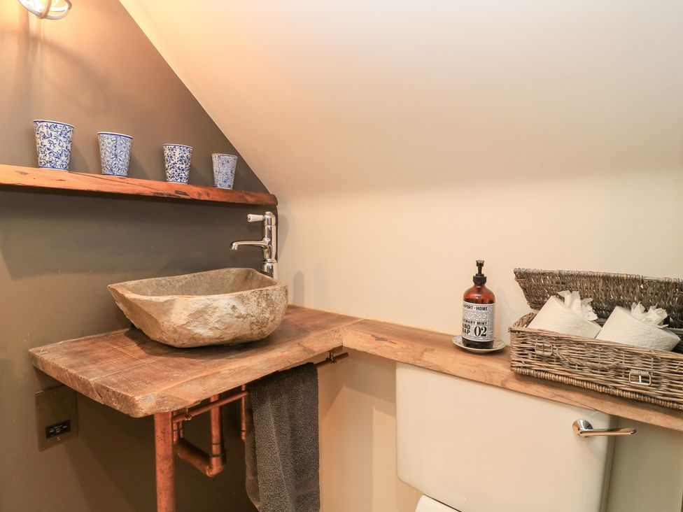 A bathroom with a stone wash basin and a toilet at Pudding Hill Barn Cottage in Bibury