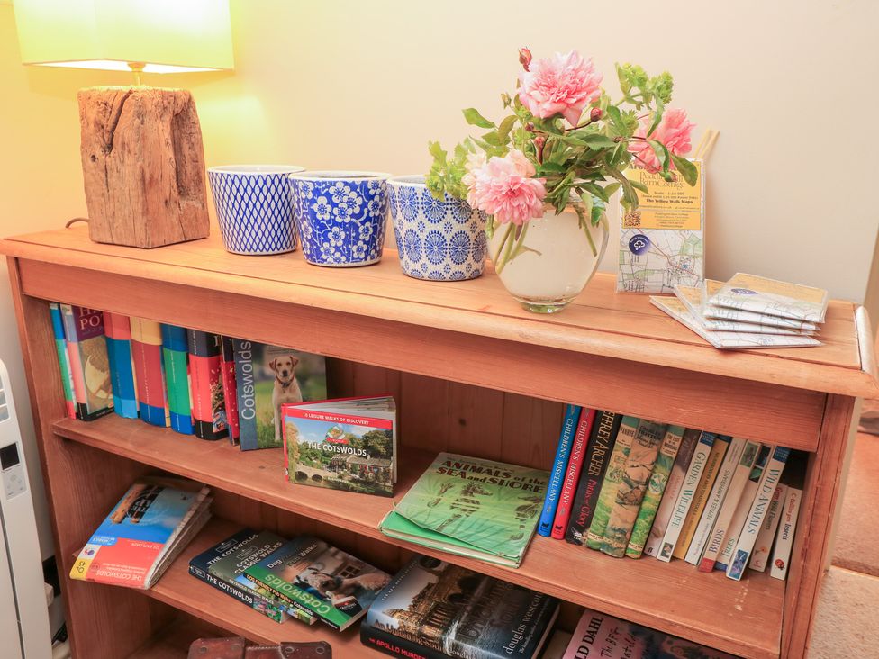 A shelf with books and decorative items at Pudding Hill Barn Cottage Bibury