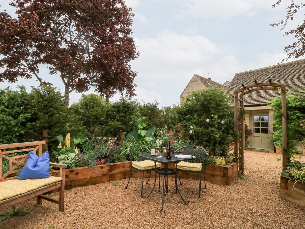 A garden with table and chairs and a wooden bench at Pudding Hill Barn Cottage Bibury