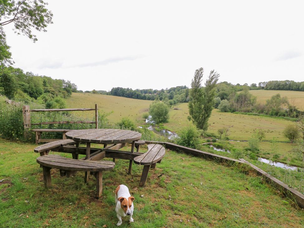 An outdoor area with a table, benches and a dog at Pudding Hill Barn Cottage, Bibury