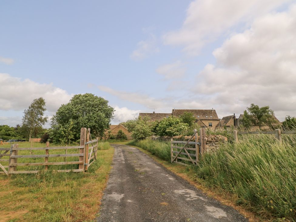 A dirt road leading to a house with trees at Pudding Hill Barn Cottage Bibury