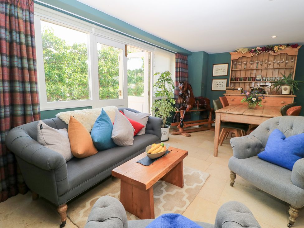 A living room with a sofa, coffee table, and dining table at Pudding Hill Barn Cottage Bibury