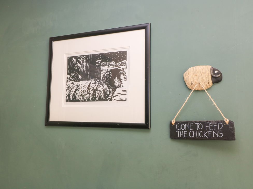 A framed artwork and a sheep decoration on a wall at Pudding Hill Barn Cottage Bibury