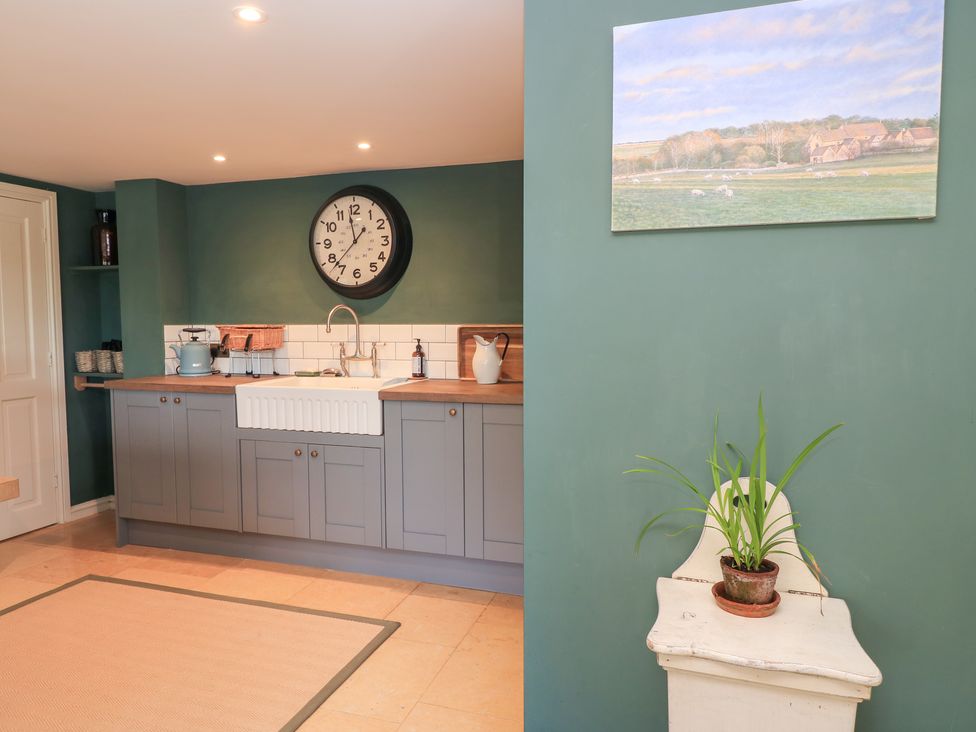 A kitchen with a sink and clock at Pudding Hill Barn Cottage Bibury