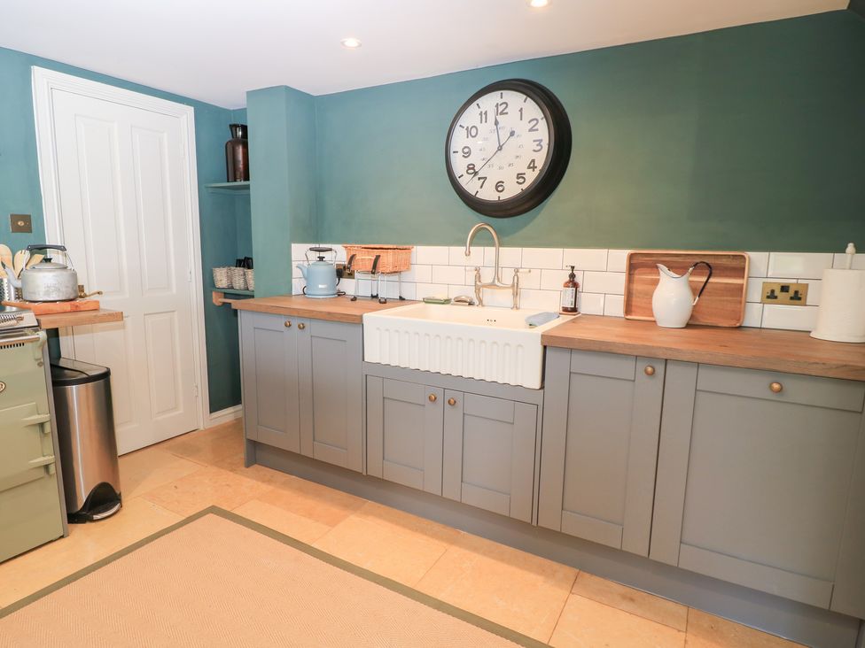 A kitchen with a sink and clock at Pudding Hill Barn Cottage in Bibury