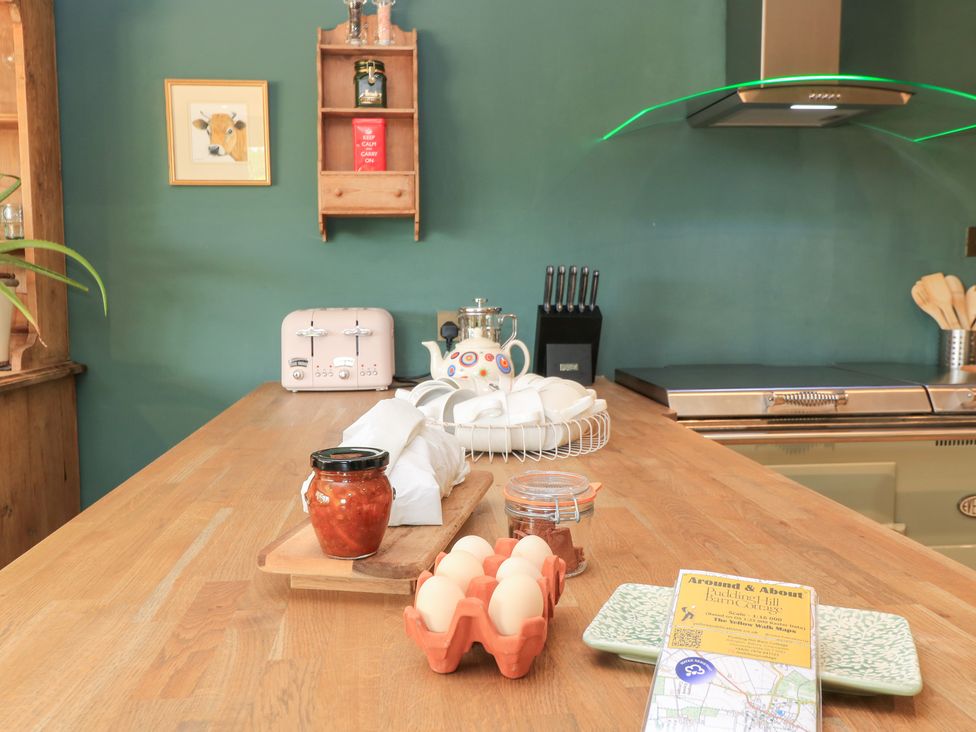 A kitchen with a wooden island and various items including eggs and a toaster at Pudding Hill Barn Cottage in Bibury