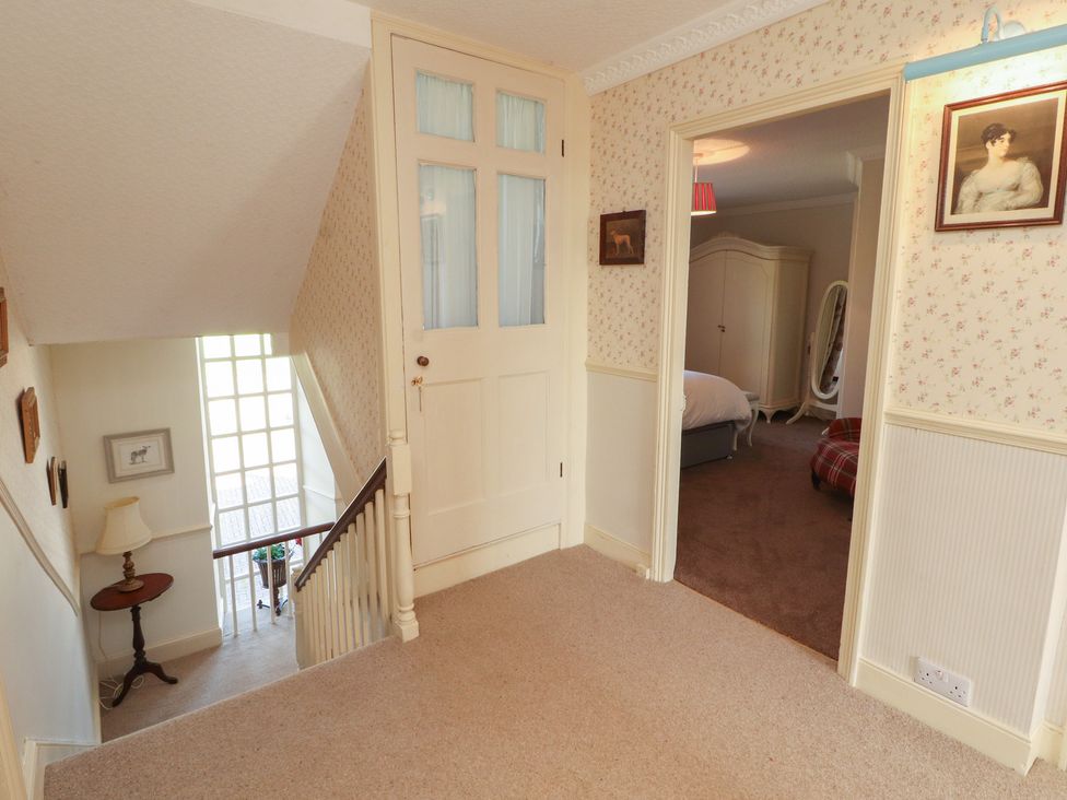 A hallway with stairs and a door leading to a bedroom at Garsdale Foot in Sedbergh
