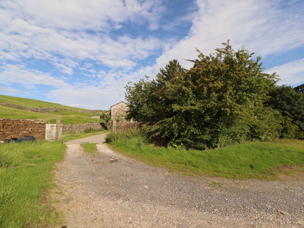A gravel road with stone walls and trees at Garsdale Foot in Sedbergh