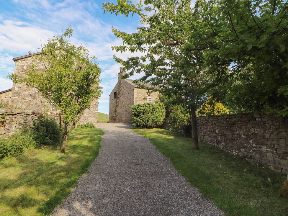 A pathway lined with trees and stone buildings at Garsdale Foot in Sedbergh