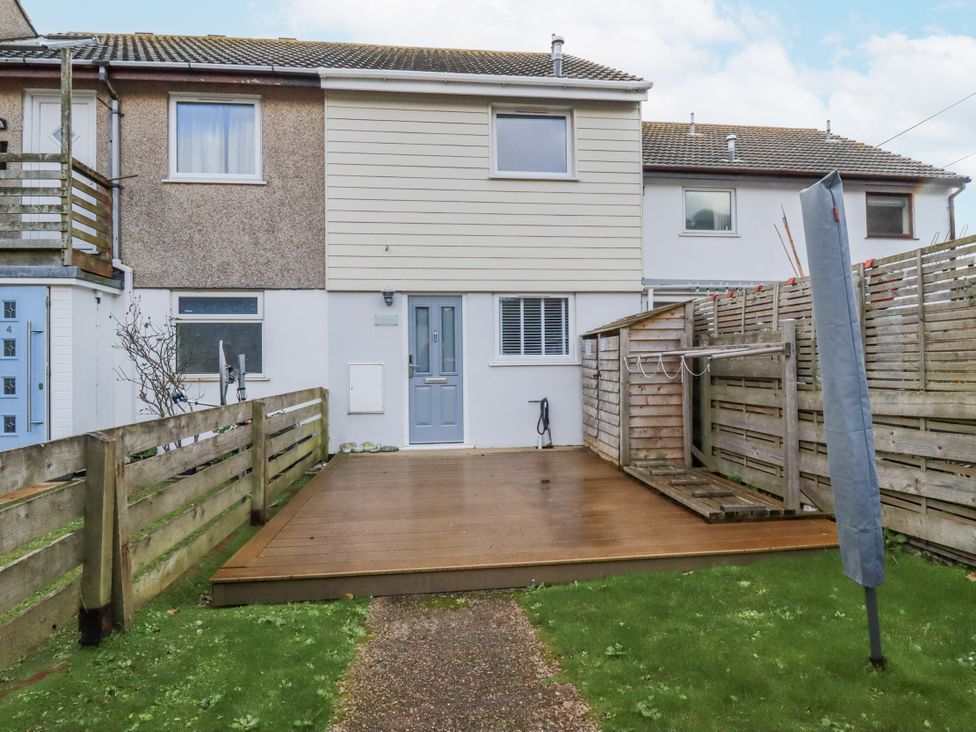 A garden with a wooden deck and laundry line at Kippy Cottage in Porthtowan
