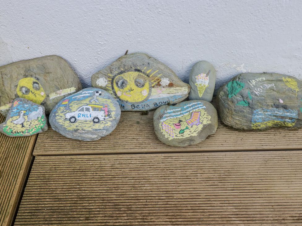 Painted rocks with various designs including a sun, ice cream, and RNLI car at Kippy Cottage in Porthtowan