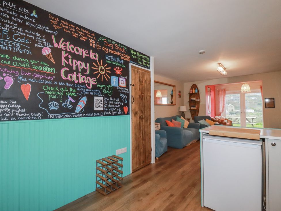 A living room with a chalkboard wall and seating arrangement at Kippy Cottage Porthtowan